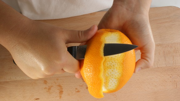 Orange wird mit einem Messer geschält