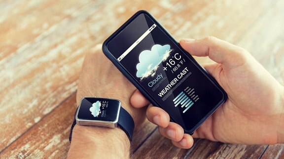 Hand mit Applewatch, auf der die Wettervorhersage zu sehen ist und Smartphone mit Wettervorhersage